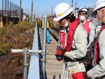 ジオテクの鉄橋の上で超音波式水位計の設置工事を行う
